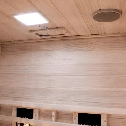 Infrared sauna interior with wooden walls, ceiling, and a control panel.