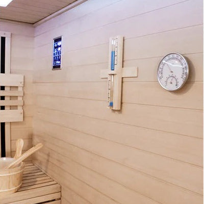 Wooden sauna interior with a thermometer and clock on the wall.
